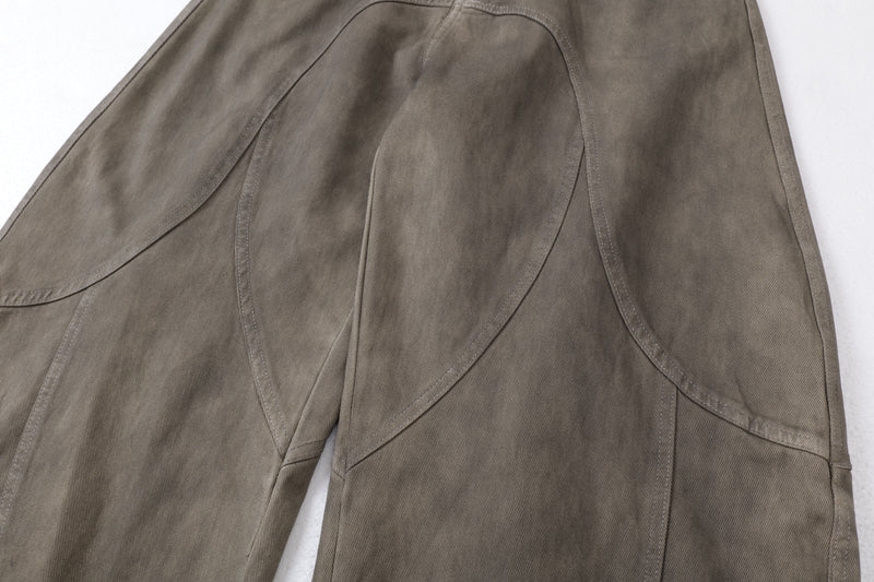 Close-up of front leg panels and curved stitching on olive-brown jeans