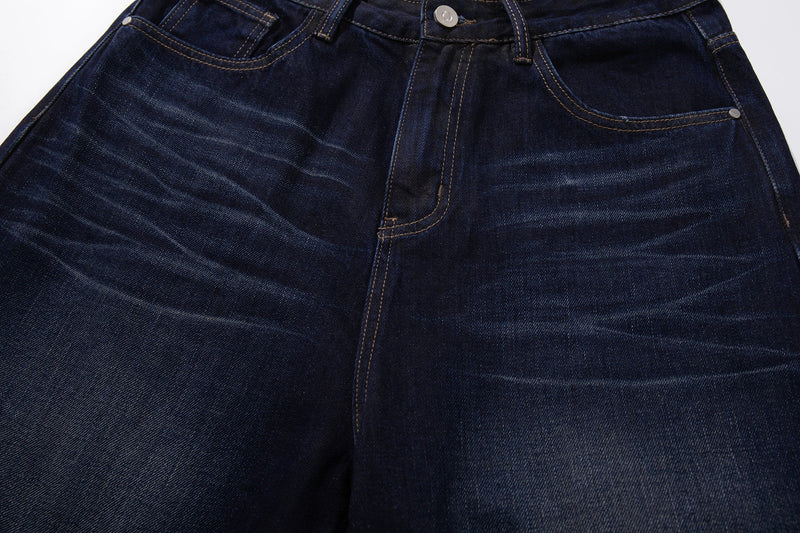 Front upper section of deep indigo jeans showing the coin pocket, fly, and light whiskering