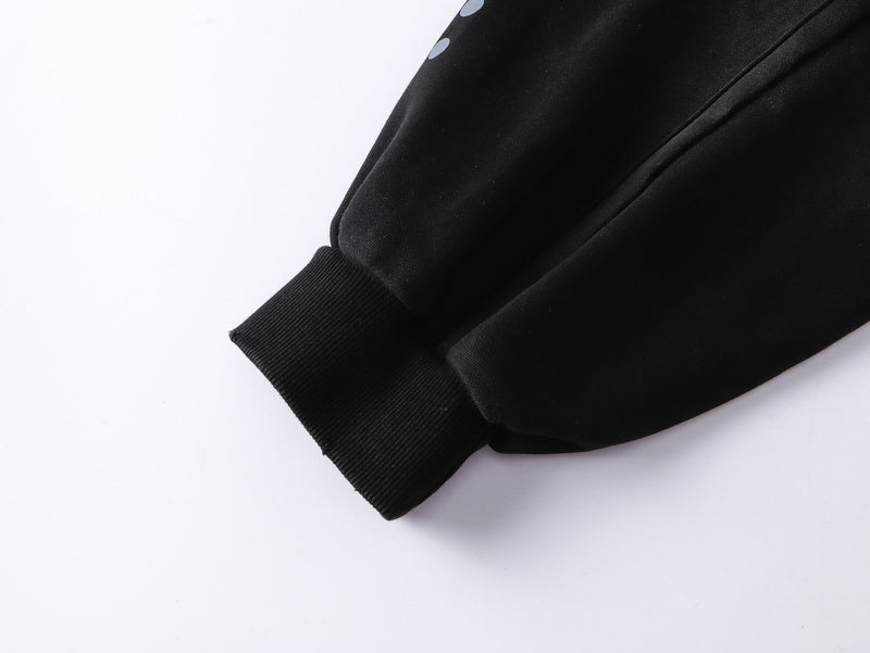 Black hoodie sleeve cuff close-up with ribbed knit trim and dotted print near the upper sleeve