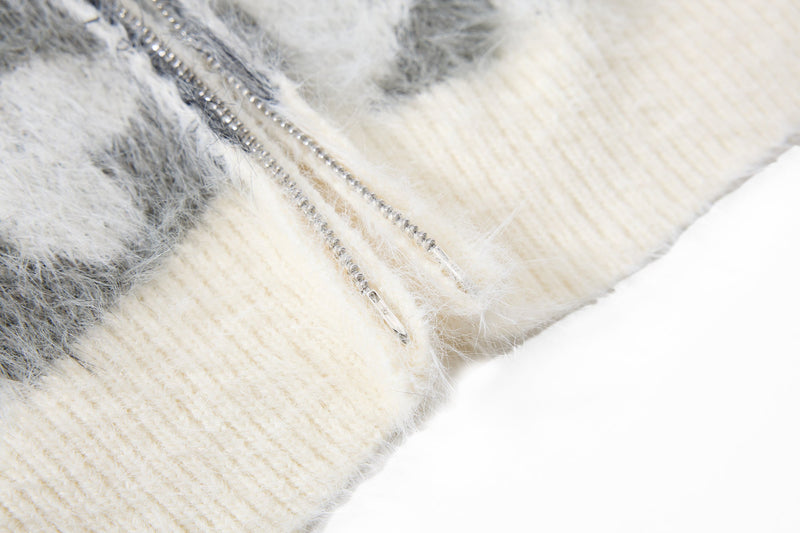 Close-up of cream ribbed hem and zipper edge on black and white faux-fur hoodie