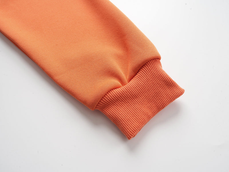 Close-up of orange hoodie ribbed sleeve cuff and smooth fabric