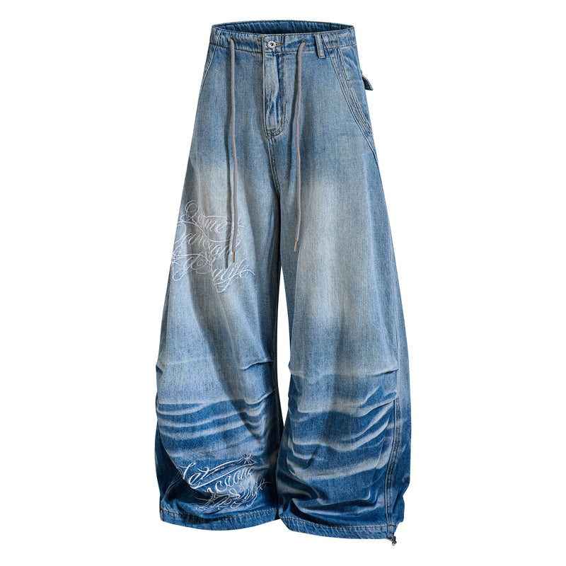 Three-quarter front view of super baggy jeans with drawstring waist and white script leg graphic