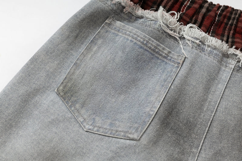 Back pocket close-up on light wash denim jeans with faded wash and plaid waistband