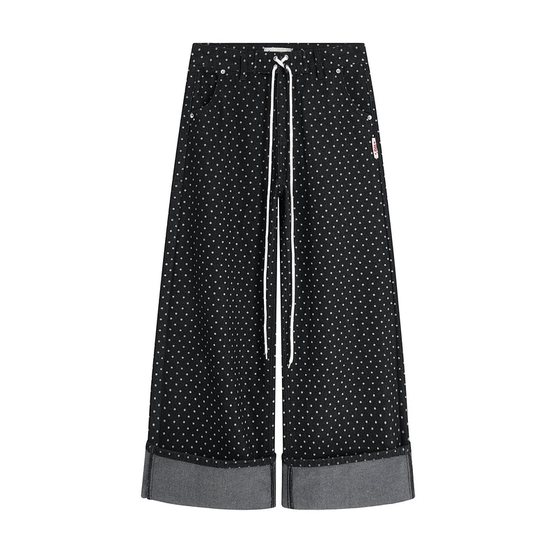 Front view of black polka-dot wide-leg denim pants with white drawstring and turn-up cuffs