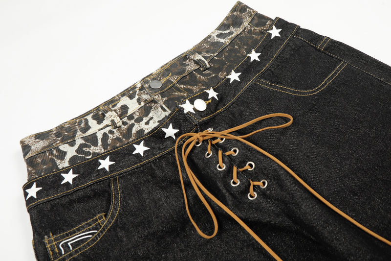 Close-up of leopard waistband, white star trim, and tan lace-up front on black jeans