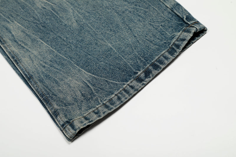Close-up of hem on faded blue jeans showing wide-leg opening and worn wash