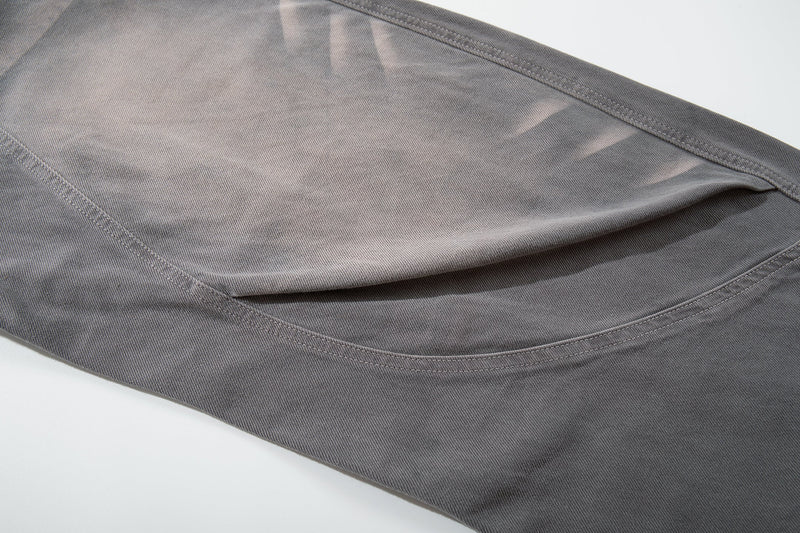 Close-up of gray jeans thigh panel with faded wash and curved seam detail