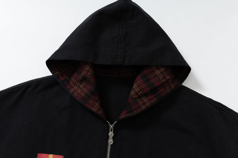 Close-up of black hoodie hood with red plaid lining and silver zipper at the neck