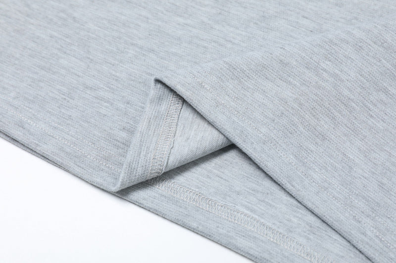 Close-up of light gray embroidered polo shirt fabric with folded hem and visible stitching detail