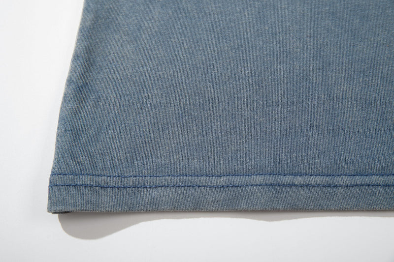 Blue vintage washed graphic T-shirt hem with visible double stitching and soft faded fabric texture