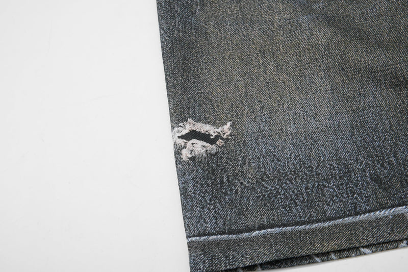 Close-up of ripped denim leg with frayed hole near the hem