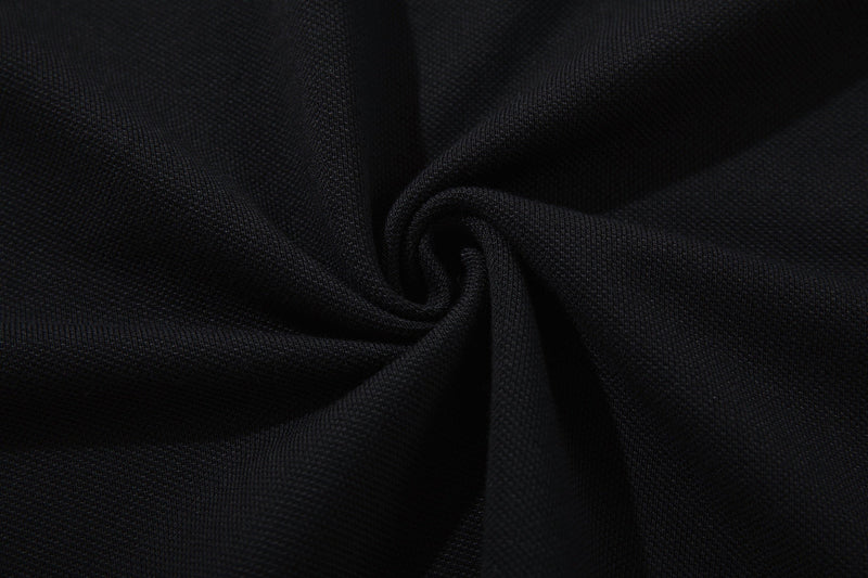 Close-up of black textured polo tee fabric with a soft draped fold, showing the gothic streetwear style material