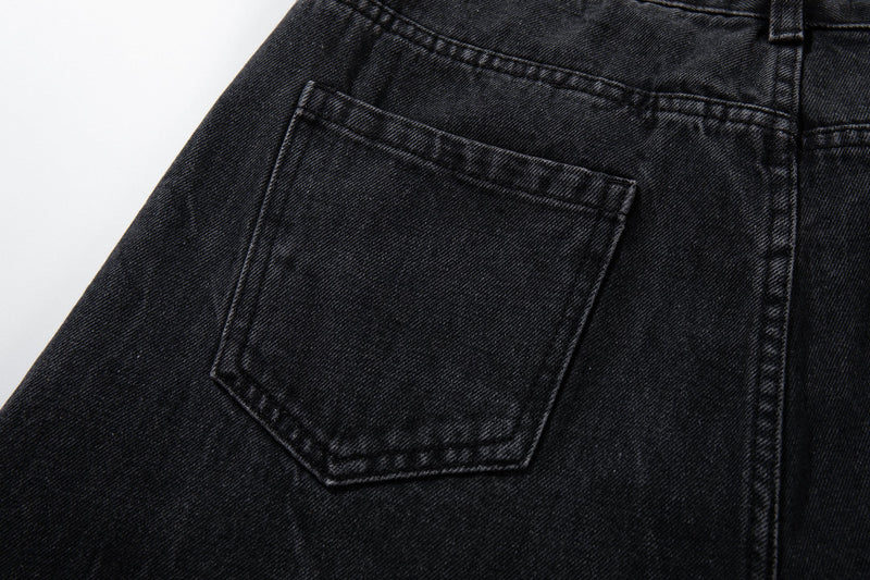 Close-up of a back patch pocket on black denim jeans with topstitched edges