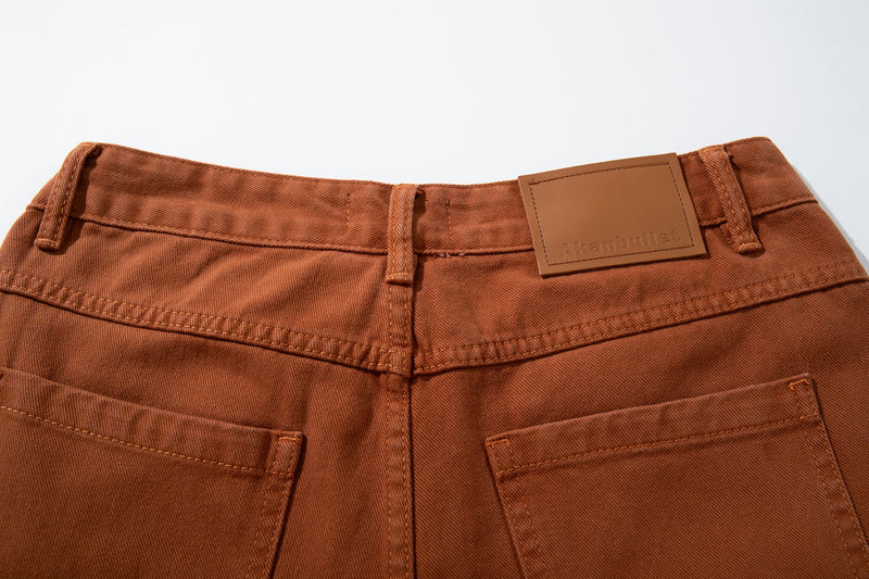 Close-up of the back waistband on rust brown jeans with belt loops and leather logo patch