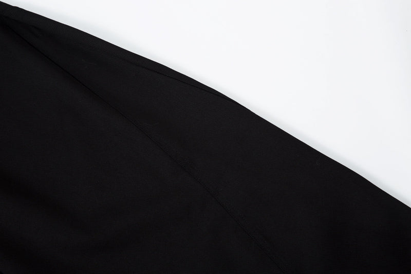 Close-up of black pants leg with diagonal seam and smooth twill texture
