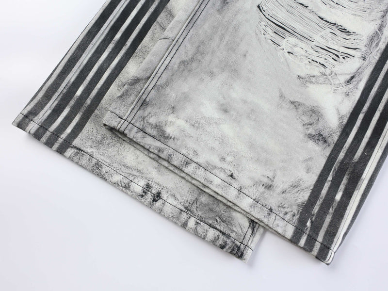 Close-up of lower leg hem on distressed jeans with black side stripes and faded wash