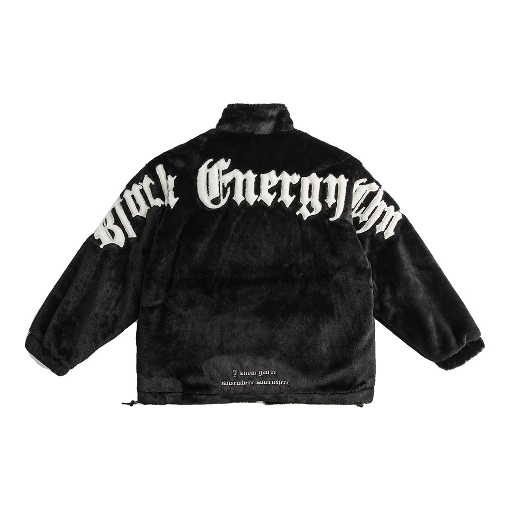 Back view of black plush fuzzy jacket with oversized white gothic lettering across the shoulders