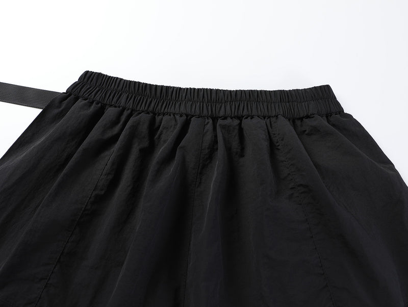 Close-up of black shorts back waistband with elastic gathering and belt end