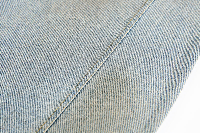 Close-up of light washed denim fabric with a single diagonal seam