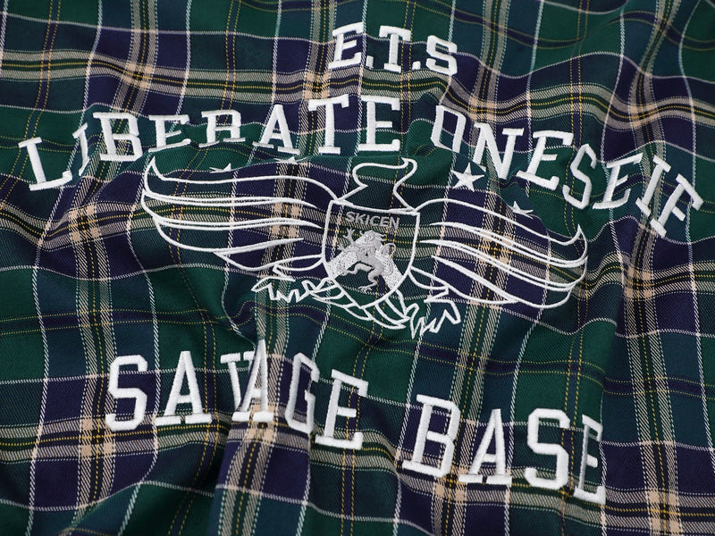 Green and navy plaid shirt with white collegiate lettering and winged crest graphic, streetwear style
