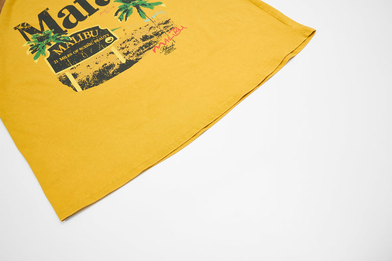 Yellow washed raglan tee with Malibu graphic and palm tree print, laid flat on a white background