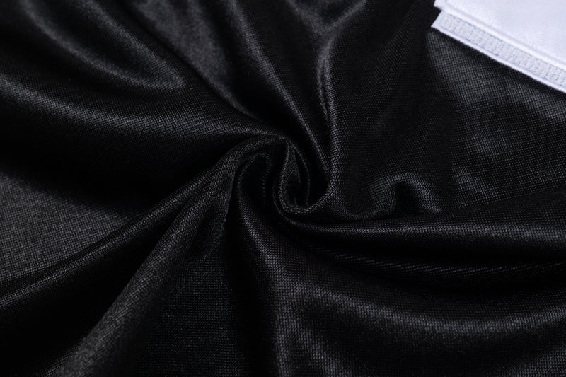 Close-up of black mesh football jersey fabric with a white patch detail on the shoulder
