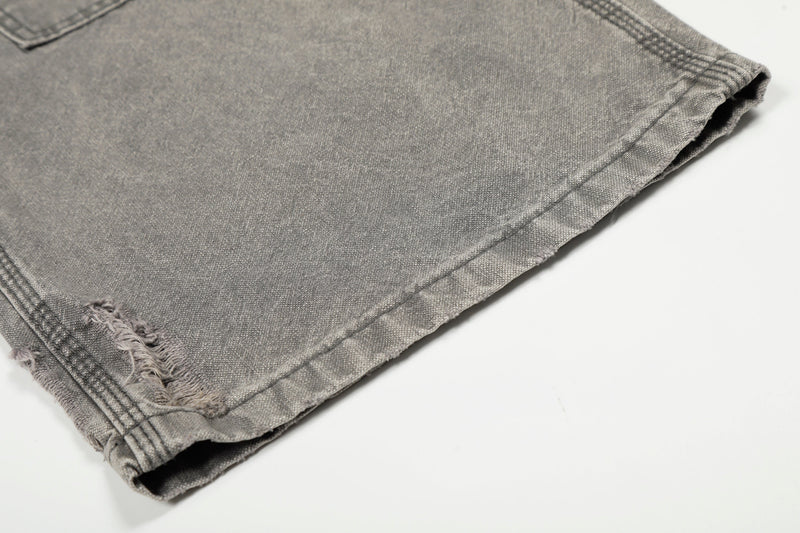 Close-up of gray jeans hem with frayed rip detail and stitched cuff