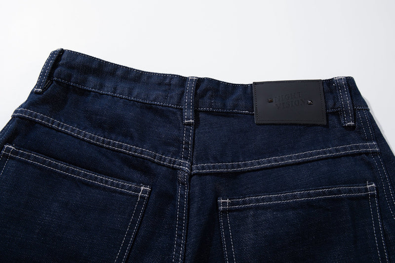 Close-up of the back waistband with dark leather logo patch and topstitching