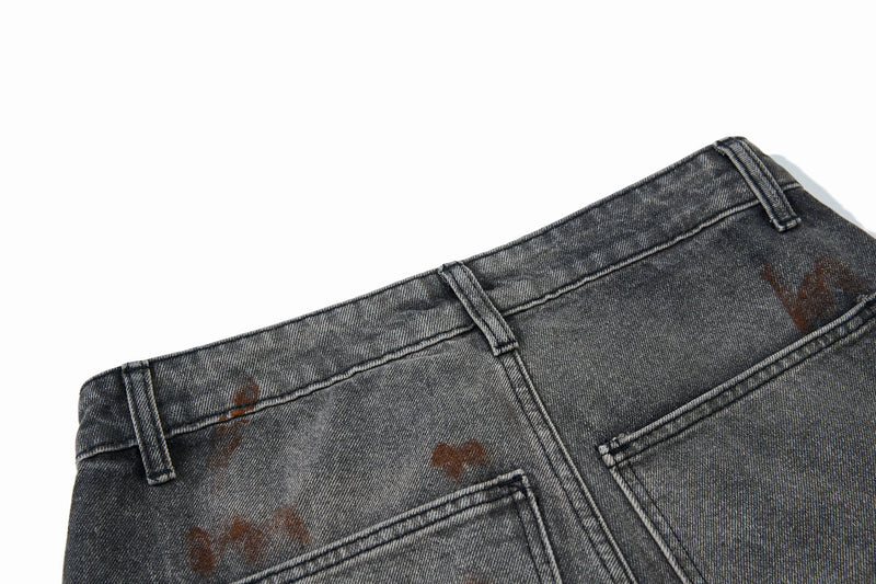 Close-up of the back waistband and pocket seams on gray cargo jeans with paint marks