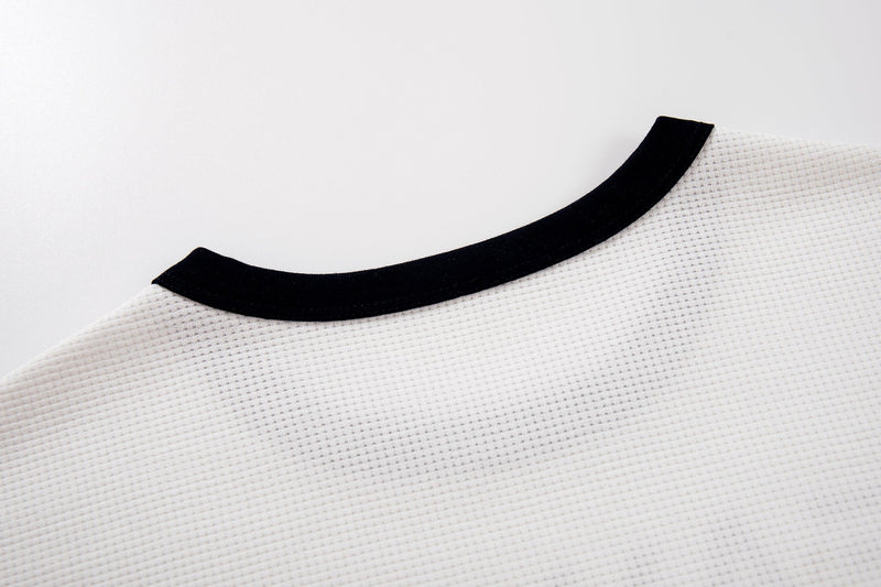 White ringer T-shirt with black collar trim and textured cotton fabric, styled in a vintage alt-music look