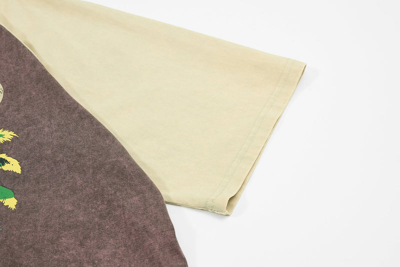 Close-up of a washed raglan tee sleeve in cream and brown with vintage palm graphic detail