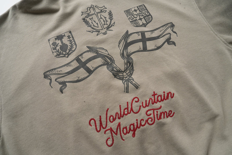 Back of taupe hoodie with black crest emblems, flag graphics, and red script text