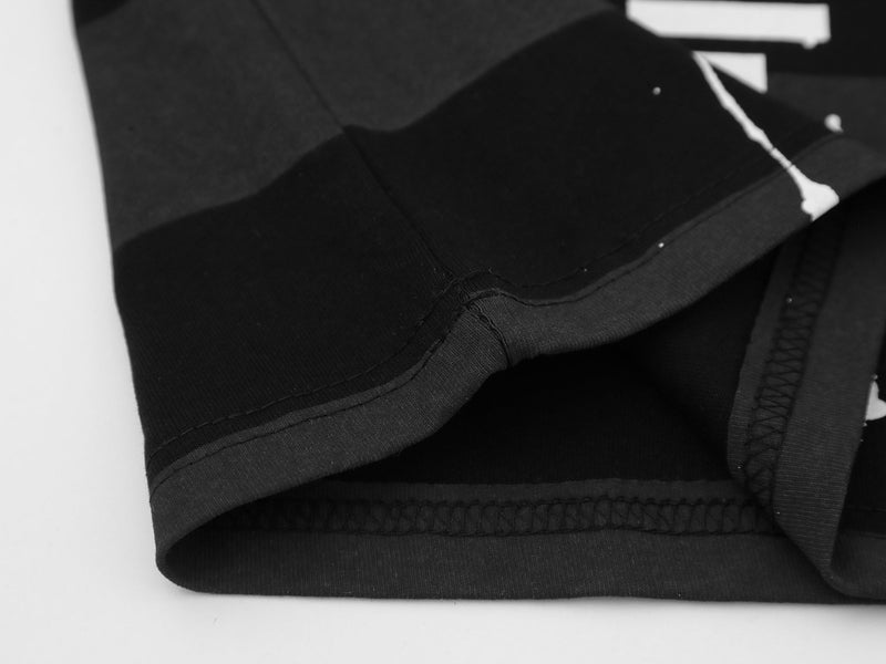 Close-up of a black oversized graphic tee with visible hem stitching and layered streetwear detailing