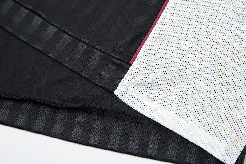 Close-up of black and white side panel seam with burgundy piping
