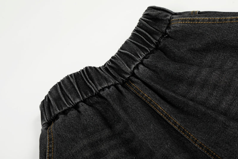 Close-up of elastic waistband on black washed denim pants with gathered stitching