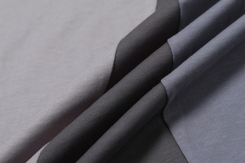 Close-up of a split-panel cotton graphic tee in gray and black streetwear style with textured fabric folds