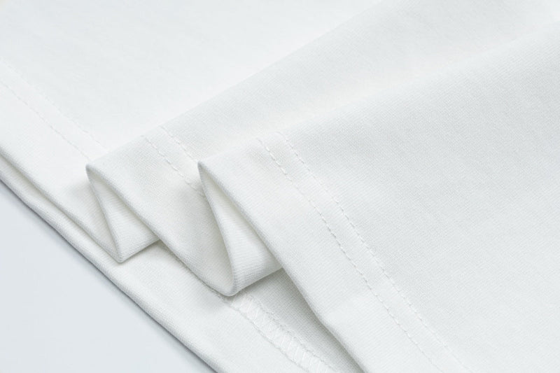 Close-up of a white cotton ringer tee sleeve with stitched hem and soft fabric texture