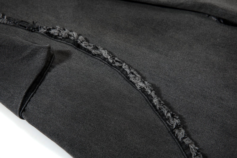 Close-up of frayed seam running across black wide-leg jeans