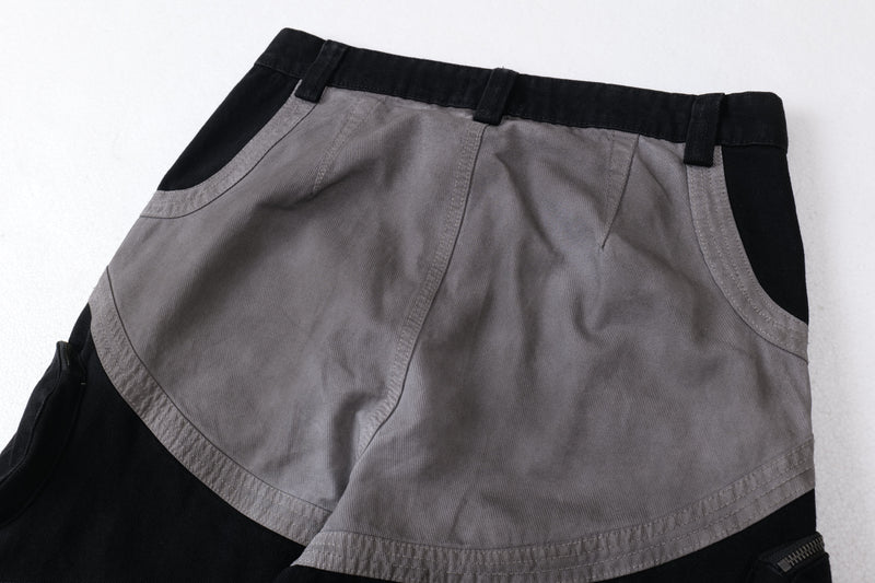 Flat lay waist view of gray and black cargo pants with belt loops and curved seam detailing