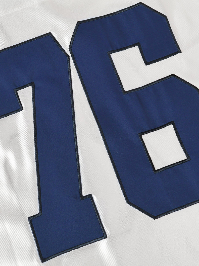 Close-up of oversized white football jersey with navy blue number 76 and black trim