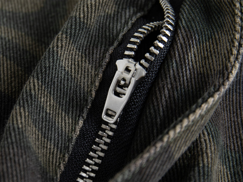 Close-up of metal zipper on dark camo cargo pants fabric