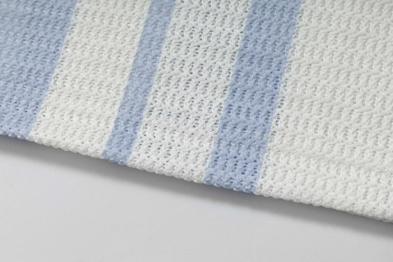 Close-up of white knit fabric with pale blue vertical stripes on a striped rugby polo shirt