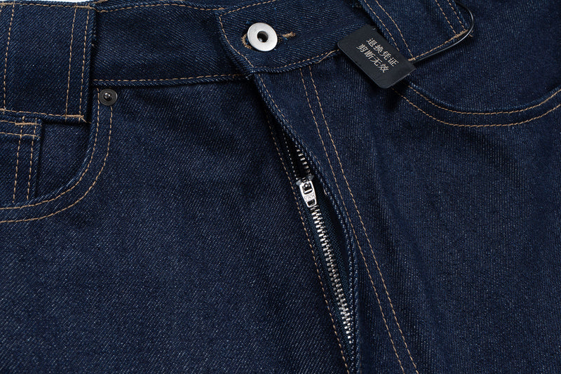Close-up of the button fly and waistband on dark indigo denim jeans with hang tag