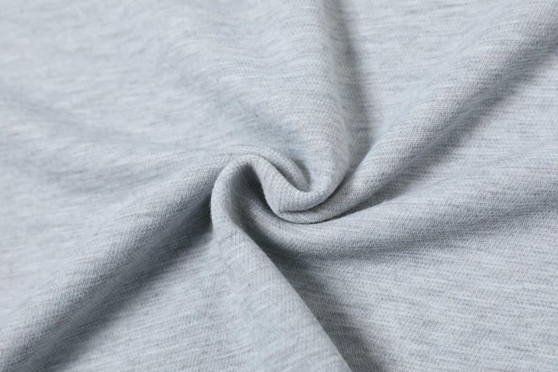 Close-up of light gray textured polo shirt fabric with soft folds and a minimal streetwear look