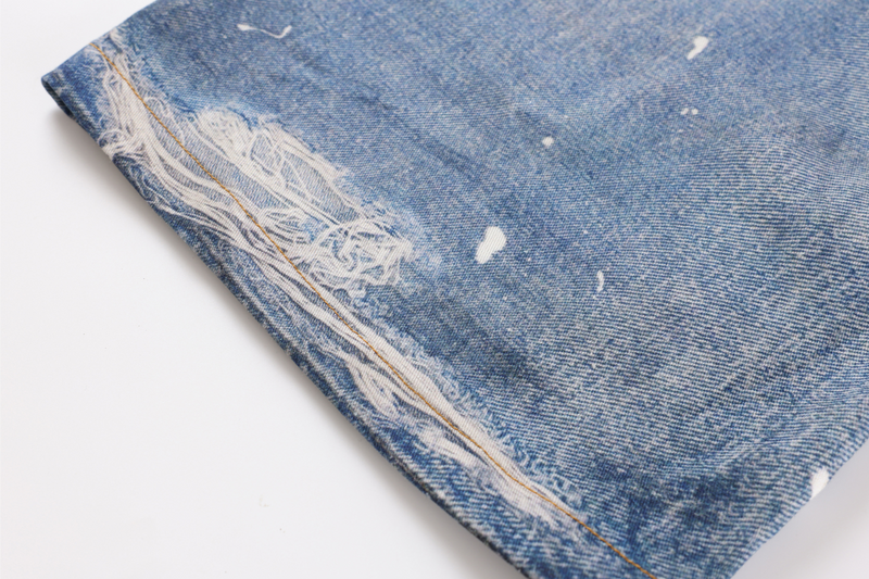 Close-up of hem and side seam on faded blue denim with frayed distressing