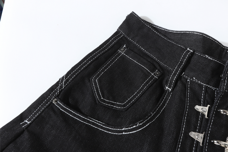 Close-up of back pocket and curved seam on black denim pants with white stitching