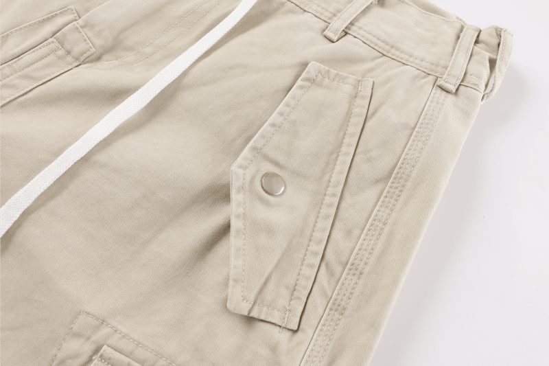 Close-up of beige cargo pants side cargo pocket with snap button and seam detail