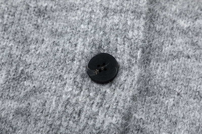 Close-up of gray cardigan button on soft fuzzy knit fabric
