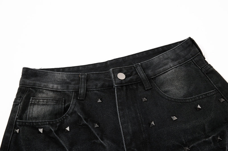 Close-up of black studded jeans waistband with button closure and front pockets