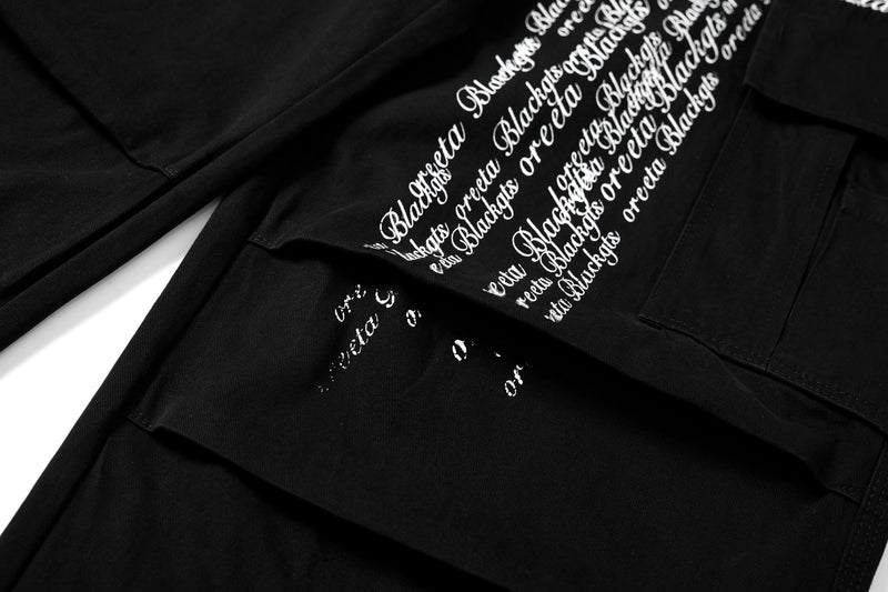 Close-up of white cross script print across black cargo pants leg